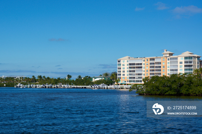 Scenic view of Bonita Springs Florida, looking across canal towards large building and boat docks.