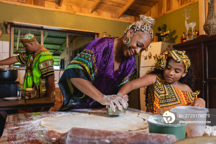 Imagen horizontal de una madre afrocaribeña en el interior de su hogar, cocinando junto a su pequeña