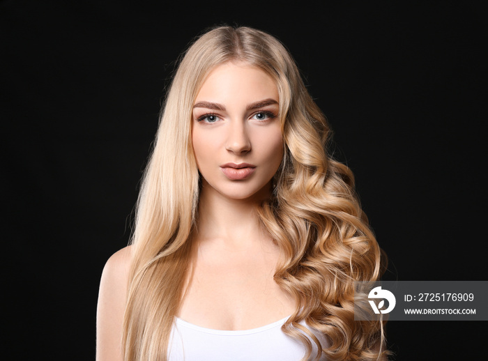 Beautiful young woman with straight and curled hair on dark background