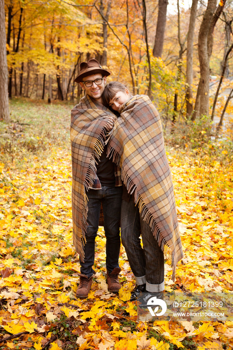 Couple wrapped in blanket in autumn forest