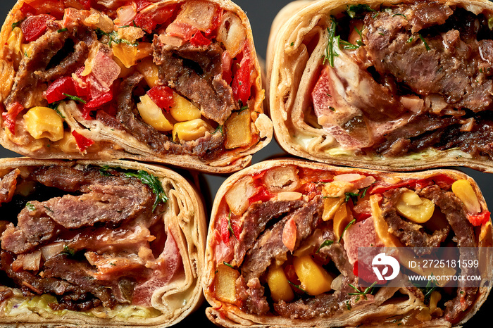 Pattern of shawarma cuts with meat and vegetables on a dark background. Close-up, selective focus