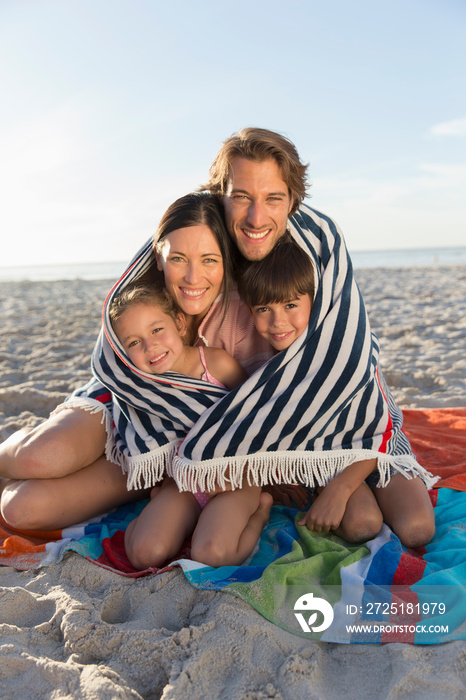 Portrait happy family wrapped in towel on sunny beach