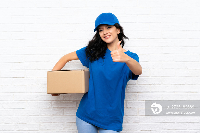 Young delivery woman over white brick wall with thumbs up because something good has happened