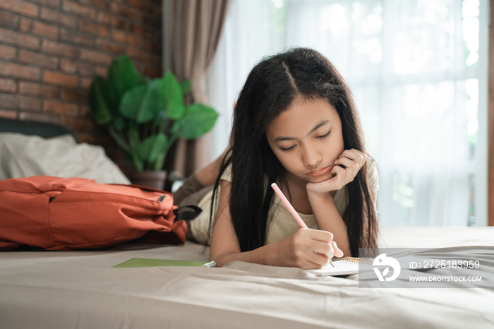 asian teenage girl studying while relaxing in the bedroom. stay home