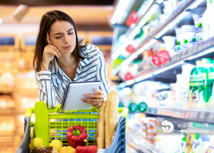 Young woman with shopping list in supermarket