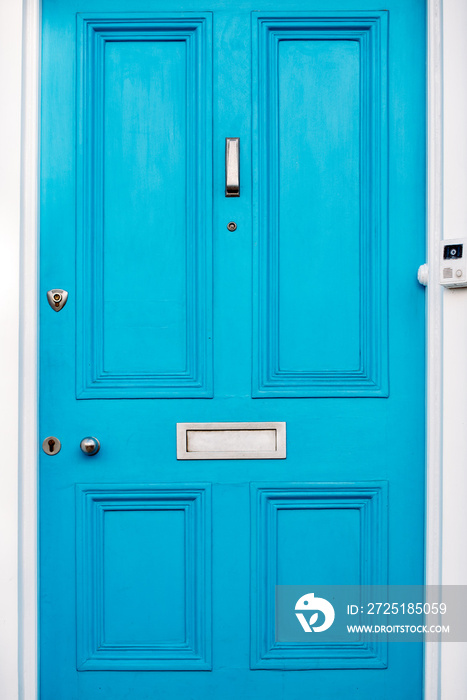 Beautiful blue door with letterbox in a white house facade in Notting Hill