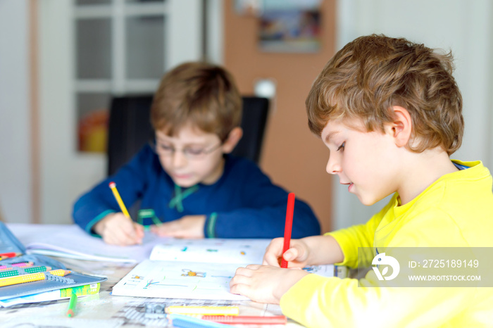 Two little kids boys at home making homework. Little concentrated children writing with colorful pen