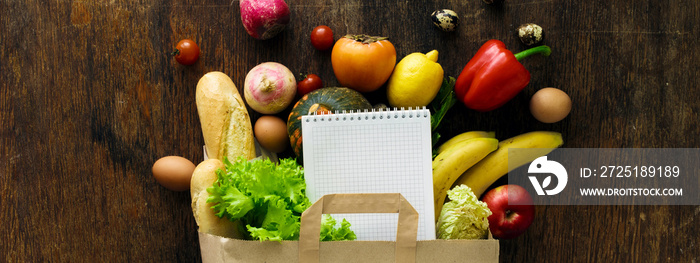 Paper bag different health food notebook wooden background Top view