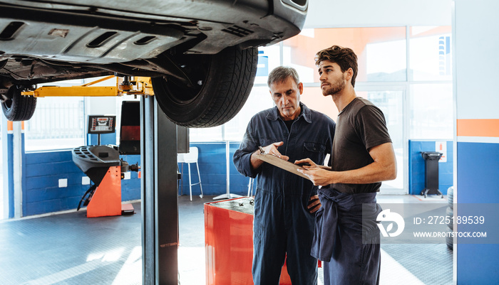 Auto mechanics making a list of repairs on car in service statio