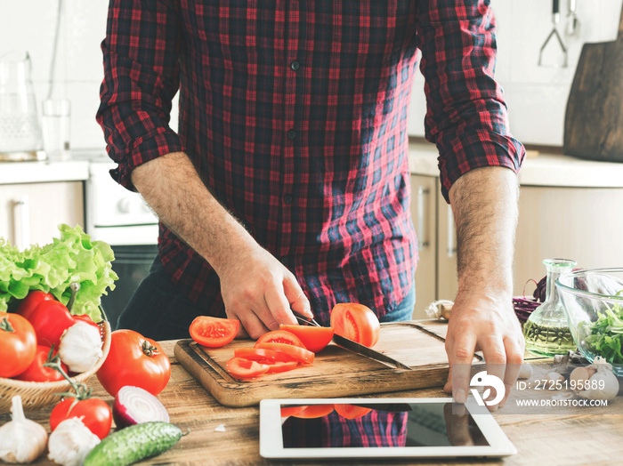 Man following recipe on tablet and cooking healthy food