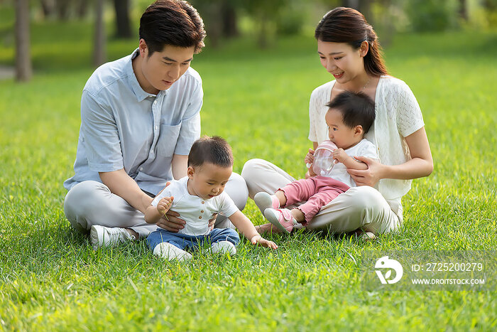 年轻父母在公园陪龙凤胎宝宝玩耍