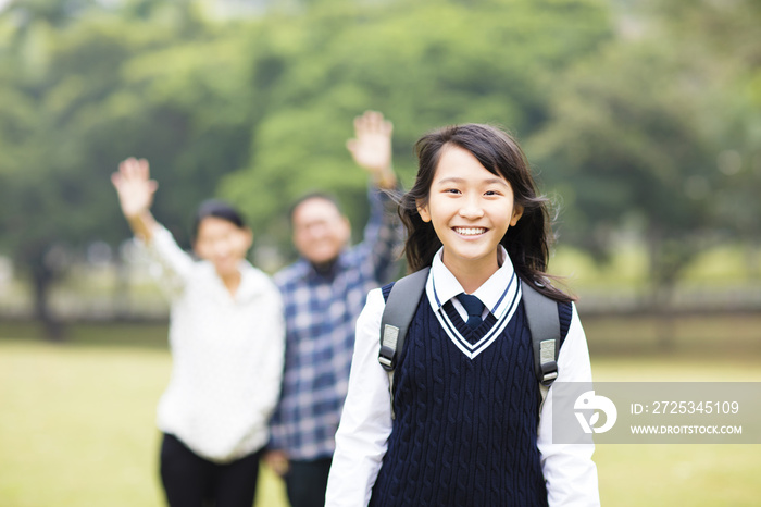 可爱的年轻学生女孩与父母在学校