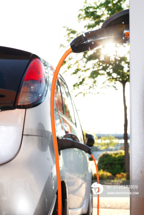 Elektroauto beim Aufladen an Stromtankstelle im Gegenlicht