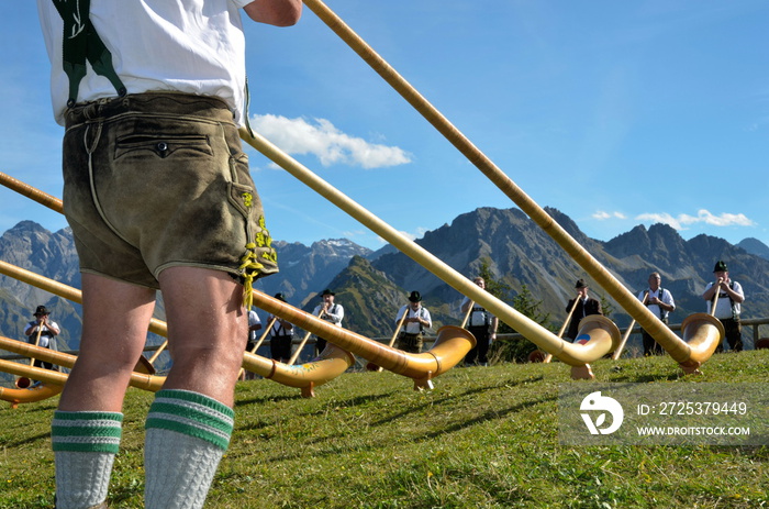 Alphornspieler mit Tracht im Gebirge