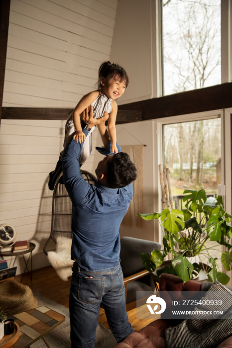 Father lifting his daughter at home