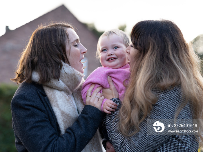 Female couple holding baby�