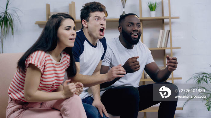 excited man screaming near happy interracial friends watching sport competition on tv.