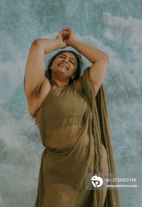 East Indian woman dancing with arms overhead smiling and laughing