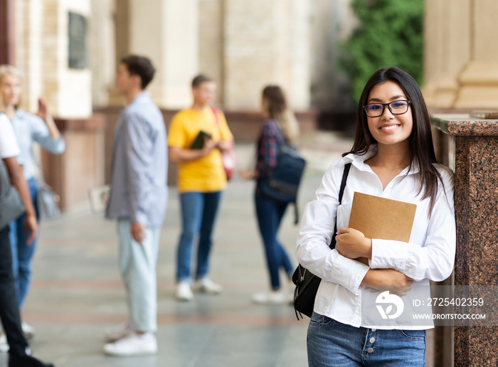 University life. Happy asian girl holding books and smiling