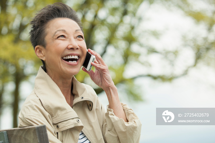 Middle-aged Asian woman having a laugh while on cell