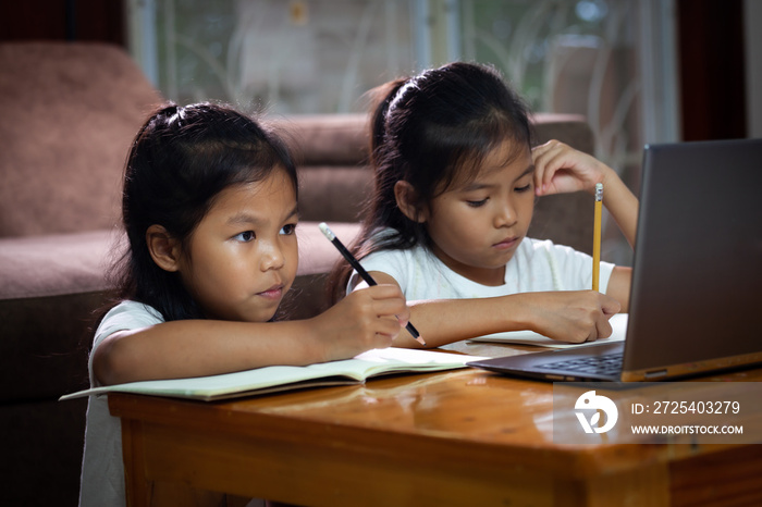 两个亚洲女孩用笔记本和姐姐一起学习在线技术。概念