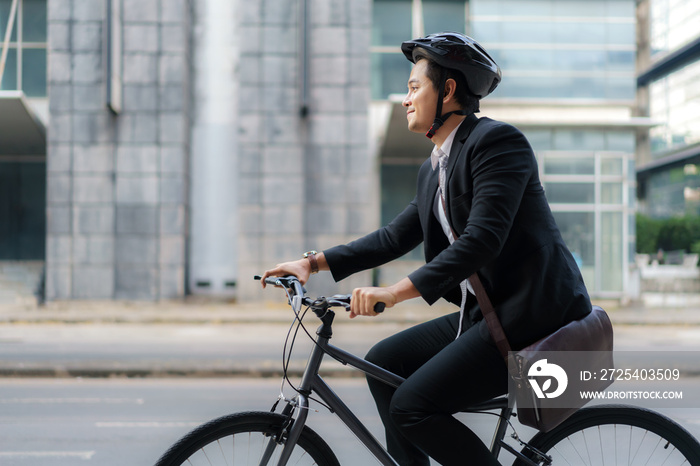 Asian businessman in a suit is riding a bicycle on the city streets for his morning commute to work.