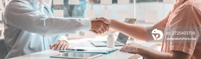 Two men holding hands, Asian doctor smiled shake hands with the patient congratulating him on being 