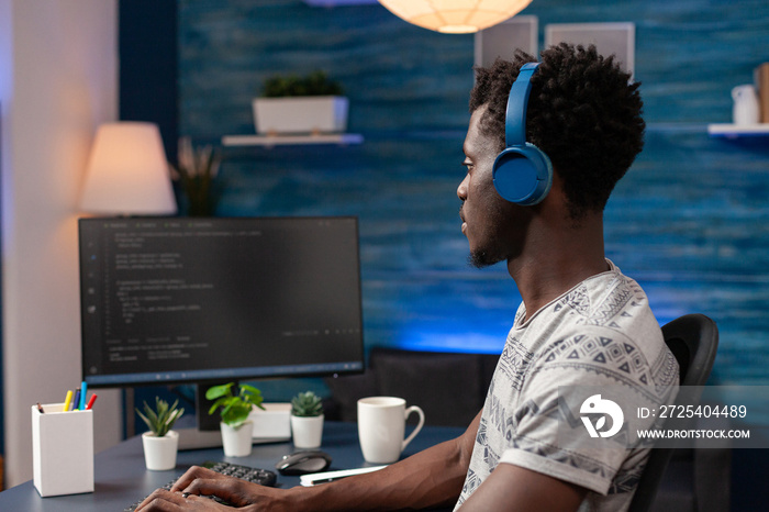 African american young programmer wearing headphone while typing security codes for business website