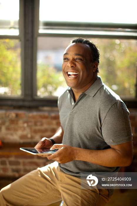 Man posing with charismatic smile holding digital tablet