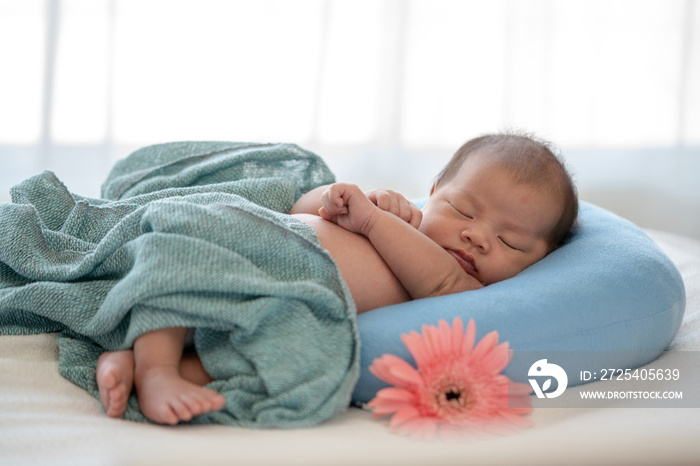 Beautiful skinny asian newborn baby girl infant sleeping on blue baby sleeper. Relaxing adorable new