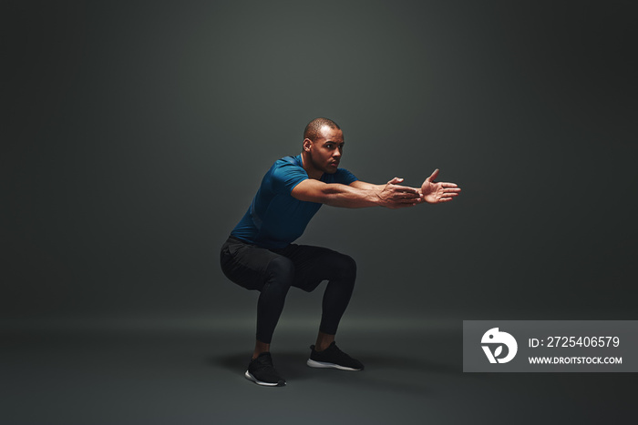 Work hard to become the best. Sportsman is stretching standing over dark background