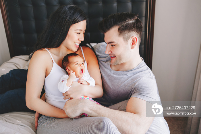 Beautiful smiling Chinese Asian mother and Caucasian father with a mixed race newborn infant baby so