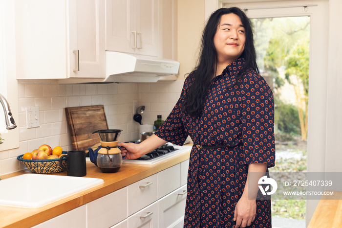 亚洲跨性别女性在厨房准备咖啡。