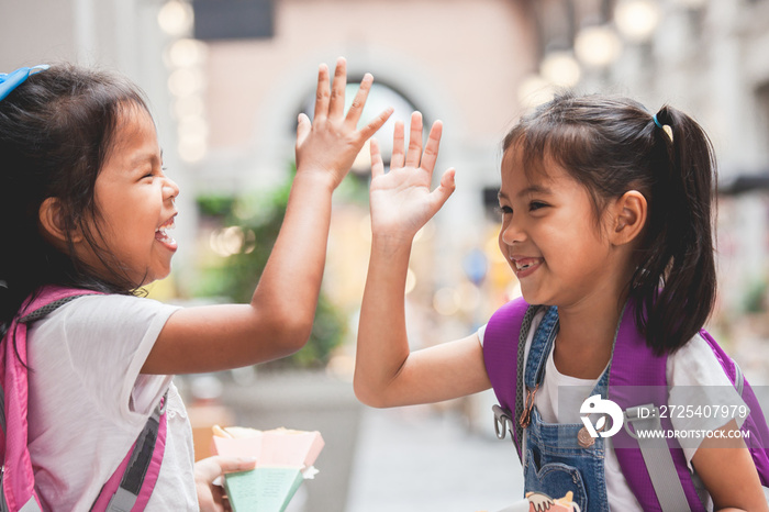 Back to school. Two cute asian child girls with school bag playing together after school in the scho