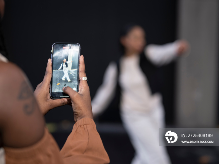 Young woman photographing?friend dancing in city