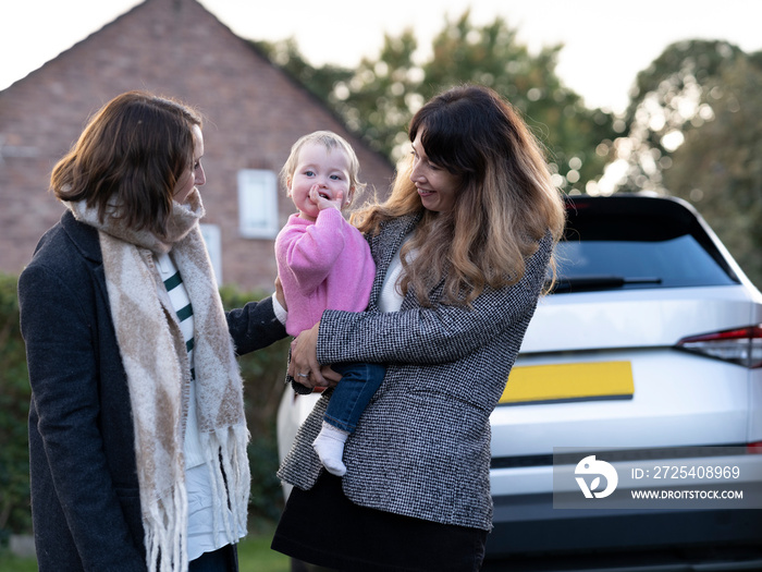 Couple with baby standing near car�