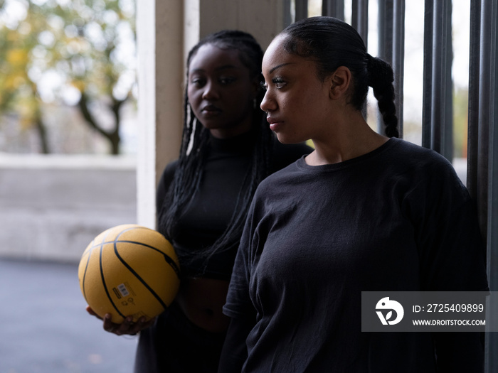 Female friends standing outdoors with basketball