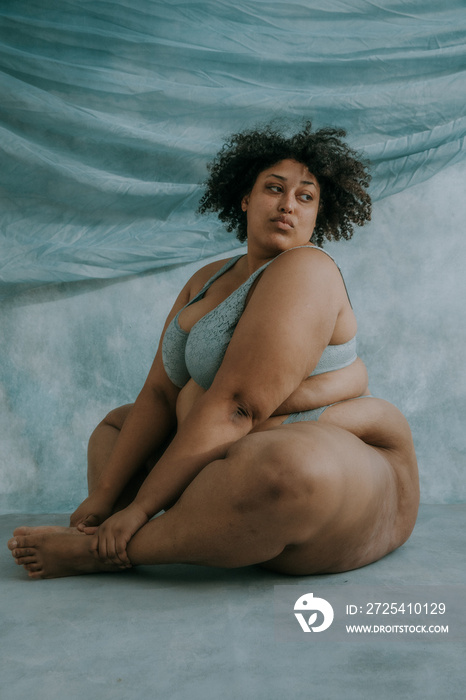 portrait of a plus size afro indigenous person sitting on the floor looking over shoulder