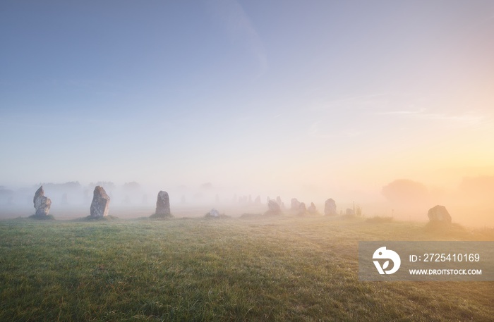 Menhir alignment view at Camaret sur mer in a morning fog at sunrise. Brittany, France. Golden light