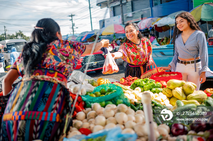 Mujeres en mercado local a comprar vegetales湿壁画。