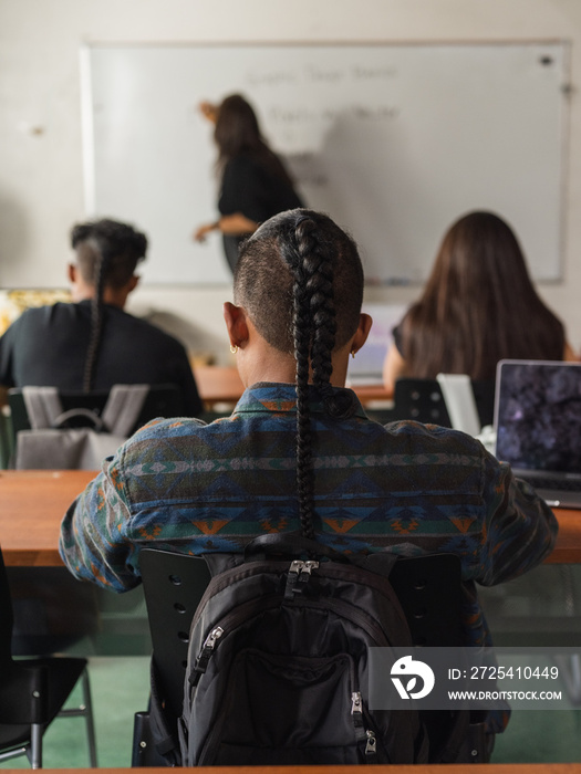 土著教师在黑板上写字，而重点放在一个扎辫子的土著学生的背上