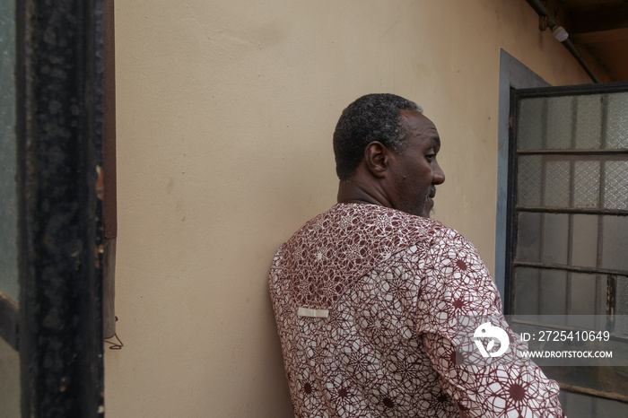 African dad in front of a wall looking to the side