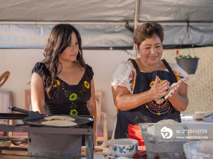 土著妇女在女儿观看时手工制作玉米饼