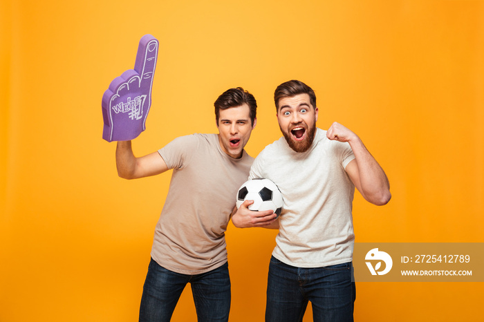 Portrait of a two joyful young men holding soccer ball