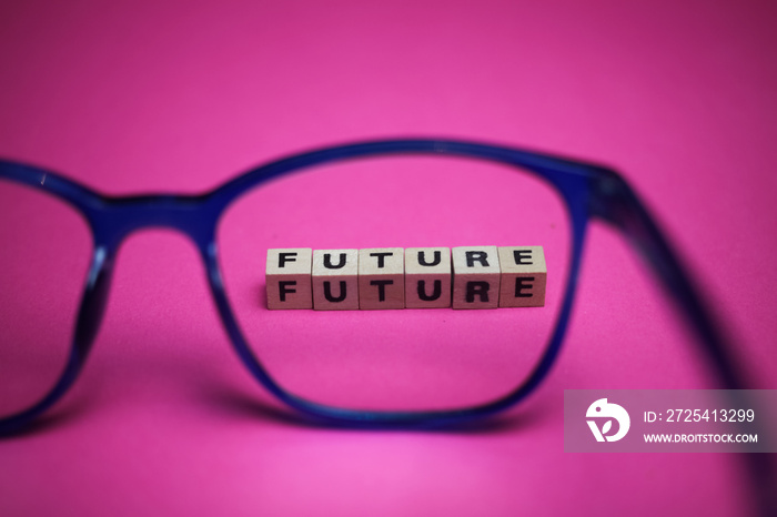 View through isolated blue eyeglasses on word future with pink background (focus on upper row of tex