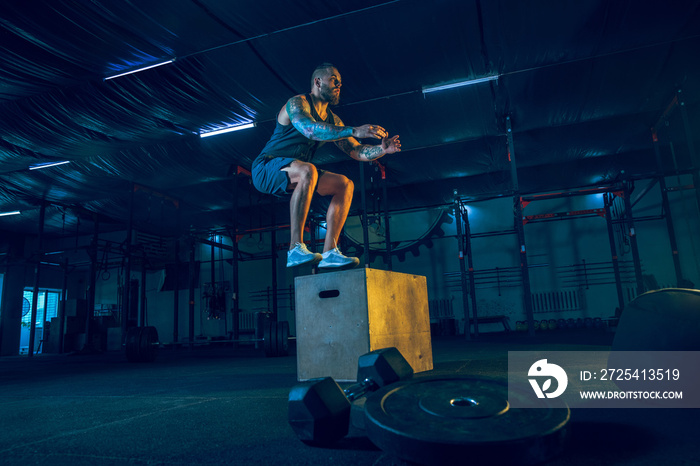 Young healthy man athlete doing exercise with the stand in the gym. Single male model training hard 