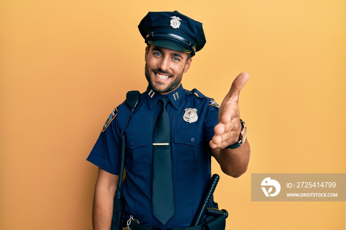 Handsome hispanic man wearing police uniform smiling friendly offering handshake as greeting and wel