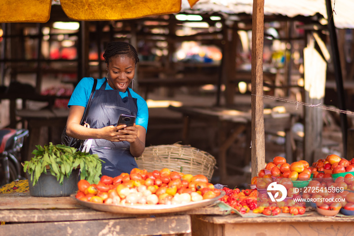 african woman feeling excited while looking at her phone in a market