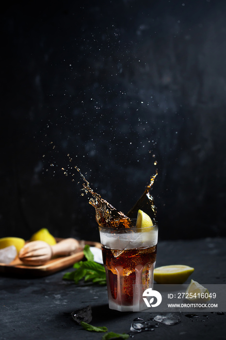 Cuba Libre or long island iced cocktail with strong drinks, cola, lemon and ice in glass, with splas