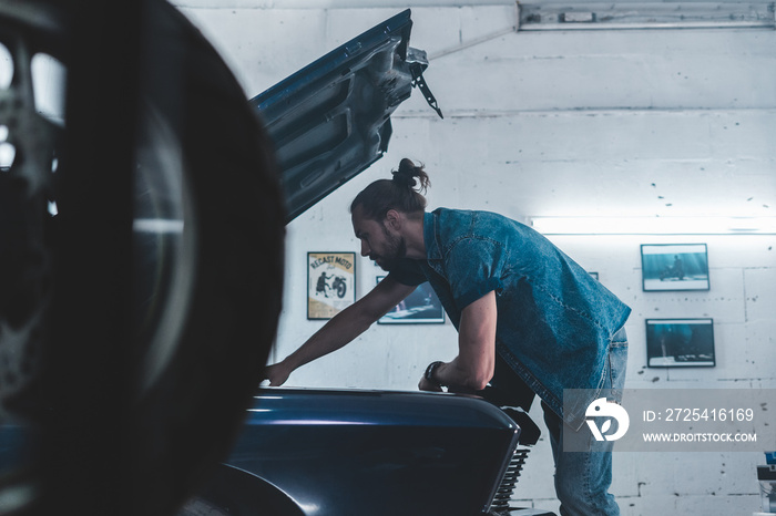 Attractive Caucasian man carrying out maintenance of his old vintage retro car